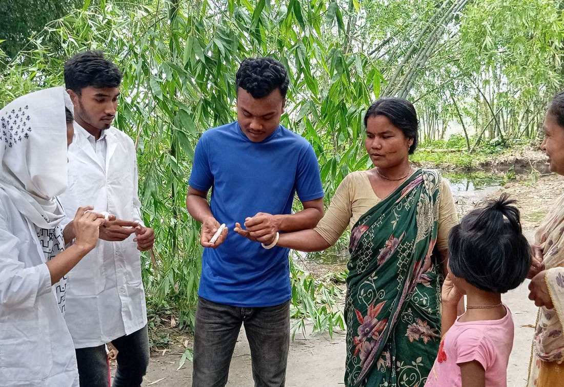 An OfP health worker testing a villager's blood sugar at an outdoor visit