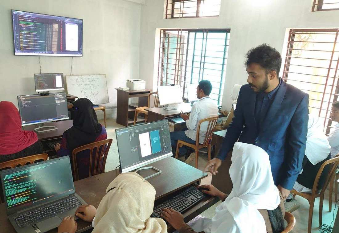 An instructor helping students learn computer programming in the OfP computer lab